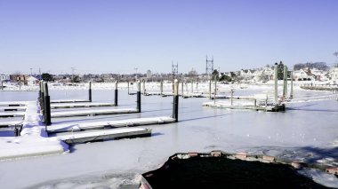NORWALK, CT, ABD - 29 Ocak 2026: Donmuş rıhtım ve su Norwalk, Connecticut 'taki olay yerini kapsıyor. Parlak gökyüzü kış belirtileri gösteriyor. Soğuk bir günde tekneler hala buzun üzerinde dinleniyor..