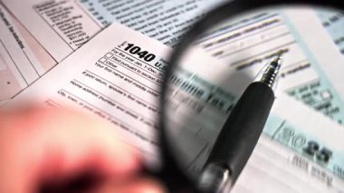 Bir ABD. Bireysel Gelir İade 1040 formu, bir kalem ve bir büyüteç gibi görünür. Vergi yılı 2025..