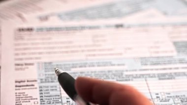 Vergi sezonunda Amerikan vergi formunun çizgilerini gösteren bir kalemle bir adamın eli.