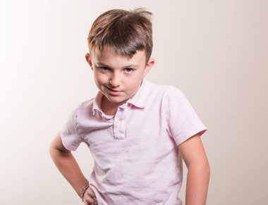 Kafkasyalı bir çocuğun portresi, günlük kıyafetler giymiş, yüzünde çirkin bir ifade, yüzünde bir gülümseme, gri arka planda izole edilmiş.