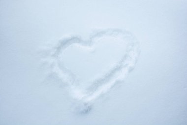 Kabarık beyaz karda bir kalp çizilir.