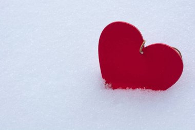 Beyaz pofuduk karda kırmızı tahta kalp