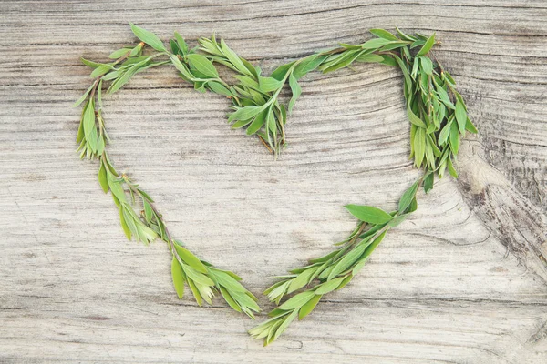 Hart van groene bladeren op een houten achtergrond. Hou van de achtergrond. — Stockfoto