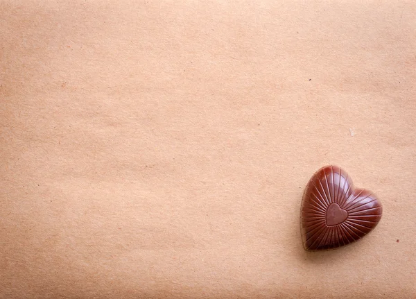 Chocolate heart over old paper — Stock Photo, Image