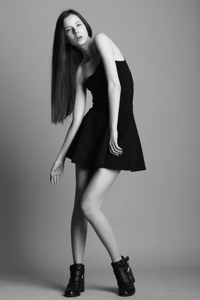 En vakker, ung modell i elegant, svart kjole som poserer i studi – stockfoto