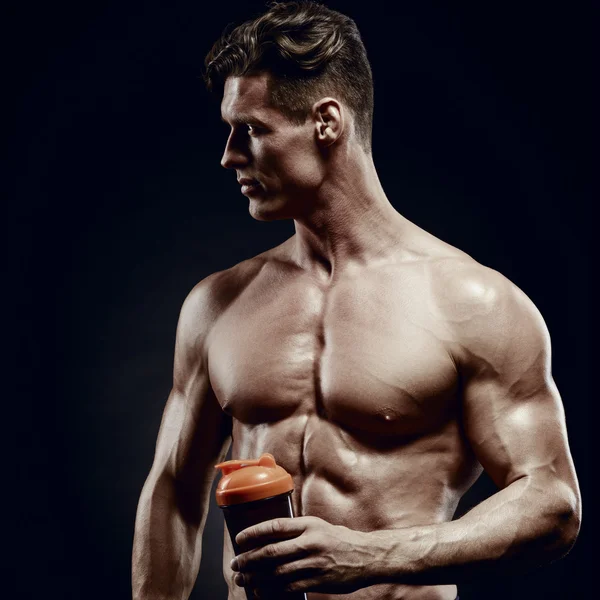 Mann Bodybuilder posiert auf grauem Hintergrund Mann hält einen Shake — Stockfoto