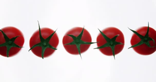 Kiraz büyüklüğünde domatesleri ez ve sık. Sulu sebzeleri ezmek temiz beyaz arka planda meyve suyu ve hamuru sıçratıyor. Taze kırmızı domates sıkıyorum. Atış stili — Stok video