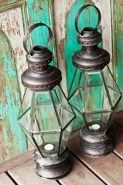 Old metal outdoor candle lamp stands on wood floor near mint woo