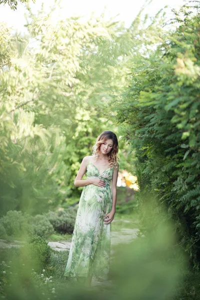 Donna incinta godendo parco estivo, indossando lungo abito bianco, tenendo in mano mazzo di fiori, all'aperto, nuovo concetto di vita. umore fresco — Foto Stock