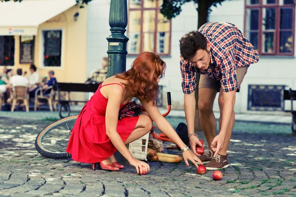 Man fell down from the bicycle and woman help him to collect products — Stock Photo, Image