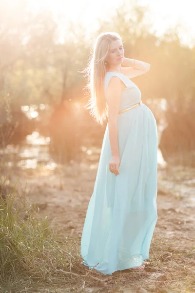 Femme enceinte aux longs cheveux blonds posant dans un parc ensoleillé. jeune — Photo