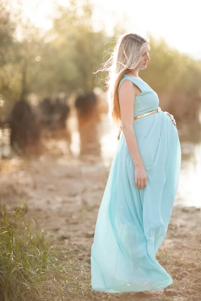 Zwangere vrouw met lang blond haar poseren in zonnig park. jonge — Stockfoto