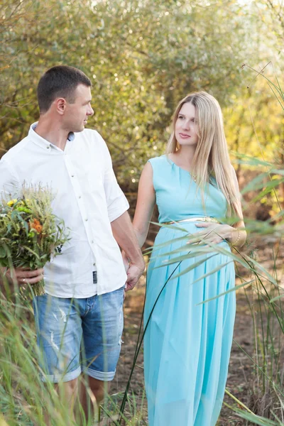 Happy and young pregnant couple walking and enjoing nature — Stock Photo, Image