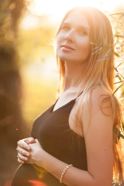 Pregnant woman with long blond hair posing in sunny park. young — Stock Photo, Image