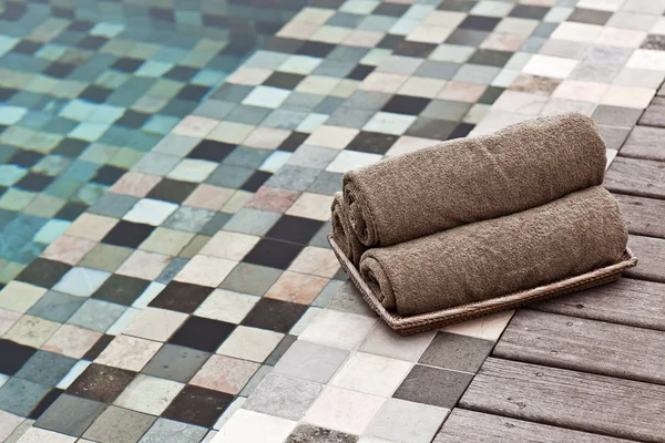 Toalhas marrons em cesta de vime em uma piscina de luxo — Fotografia de Stock