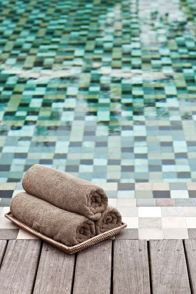 Toalhas marrons em cesta de vime em uma piscina de luxo — Fotografia de Stock
