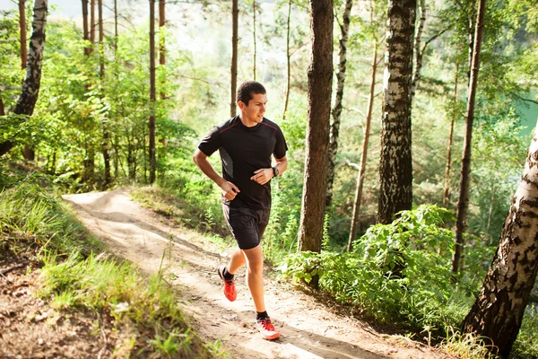 Mannelijke atleet runner uitgevoerd op weg in bos — Stockfoto