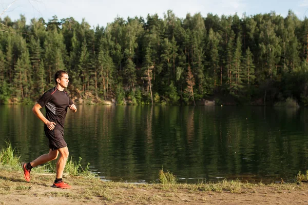 Un athlète coureur sur la route en forêt — Photo