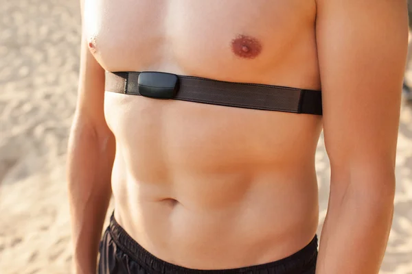 Athletic man on open road with monitor around chest on a sunny d — Stock Photo, Image