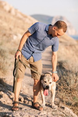 Genç beyaz erkek köpekle gündoğumu sırasında yürüyüş