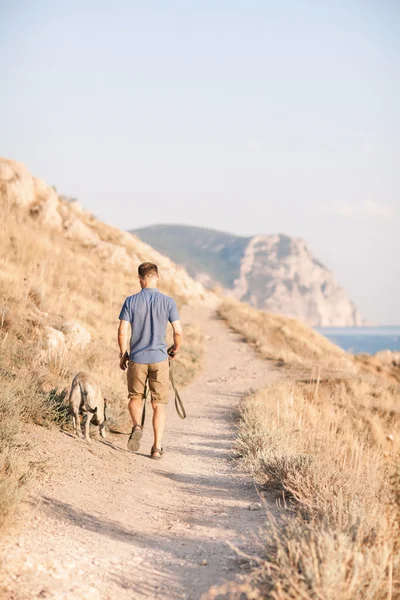 Jeune caucasien mâle marche avec chien pendant le lever du soleil — Photo