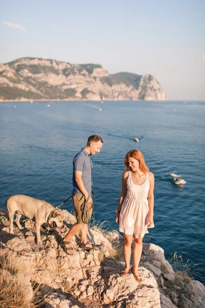 Un par de tipos jugando con su perro en la montaña cerca del océano. Tiempo romántico en la naturaleza con hermosa vista . —  Fotos de Stock