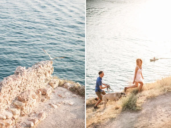 Par killar leker med sin hund på berget nära havet. Romantisk tid i naturen med vacker utsikt. — Stockfoto