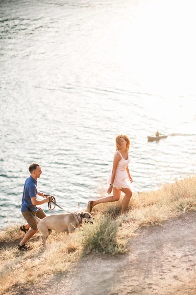 바다 근처 산에 그들의 강아지와 함께 재생 하는 사람의 커플. 아름 다운 경치와 자연 속에서 낭만적인 시간. — 스톡 사진