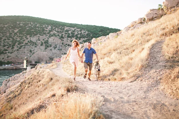 Deux gars qui jouent avec leur chien sur la montagne près de l'océan. Temps romantique dans la nature avec une belle vue . — Photo