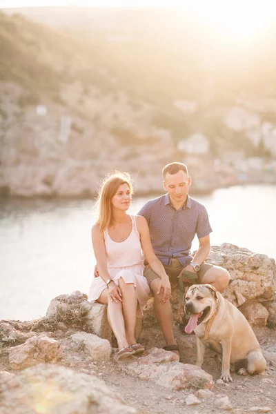 Couple of guys playing with their dog on the mountain near ocean. Romantic time in nature with beautiful view. — Stock Photo, Image