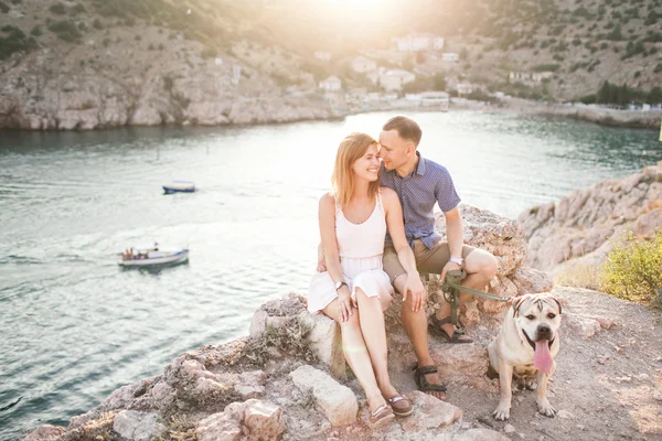 Couple of guys playing with their dog on the mountain near ocean. Romantic time in nature with beautiful view. — Stock Photo, Image