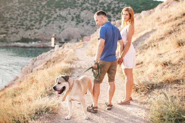Uns tipos a brincar com o cão na montanha perto do oceano. Tempo romântico na natureza com bela vista . — Fotografia de Stock