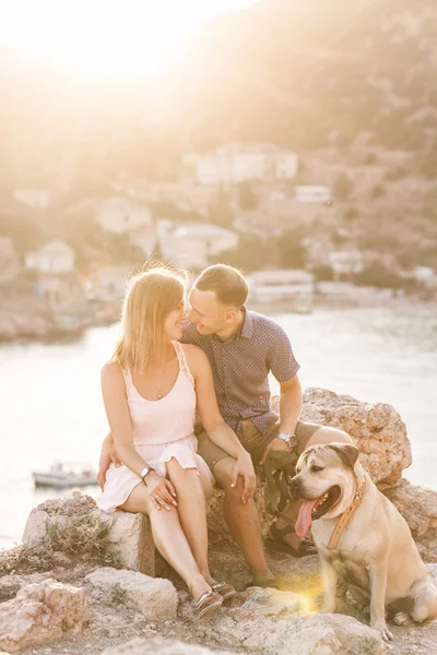 Couple of guys playing with their dog on the mountain near ocean. Romantic time in nature with beautiful view. Stock Image