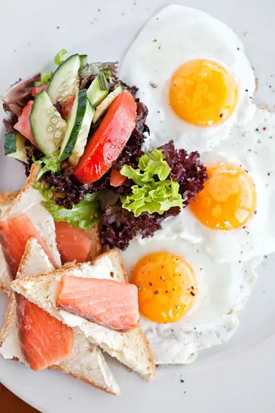 Amerikan kahvaltısı ile kızarmış yumurta, somon, tost, kızarmış balık. — Stok fotoğraf