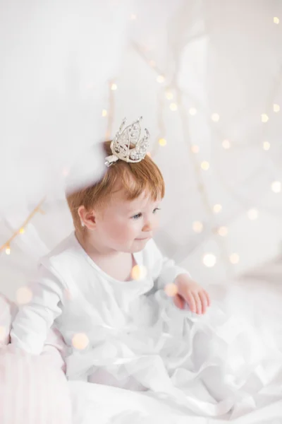 Niedliches Kleinkind Mädchen spielt auf einem Bett zwischen warmen weichen Weihnachten l — Stockfoto