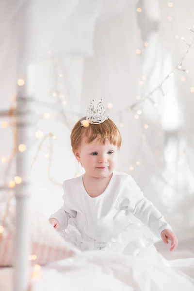 Niedliches Kleinkind Mädchen spielt auf einem Bett zwischen warmen weichen Weihnachten l — Stockfoto