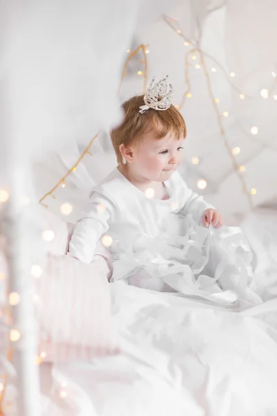 Linda niña jugando en una cama entre cálida Navidad suave l —  Fotos de Stock