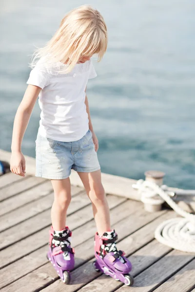 Klein meisje in rolschaatsen in de buurt van de zee — Stockfoto