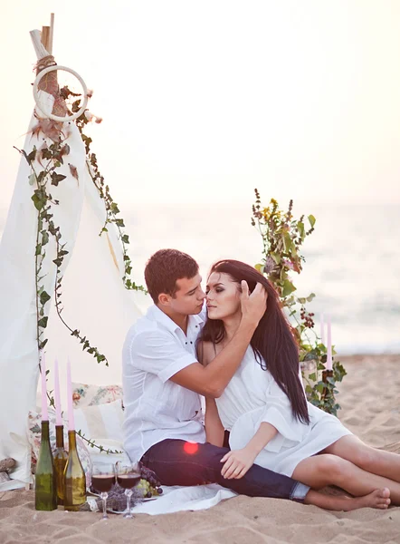 Ömhet par på stranden picknick nära wigwam — Stockfoto