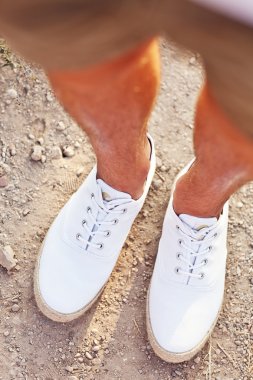 Adamın bacakları taş yolu üzerinde beyaz tenis ayakkabıları