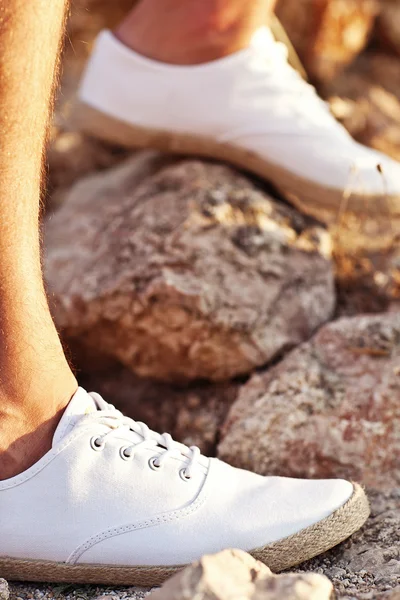 Man's legs in white tennis shoes on stone road — Stock Photo, Image