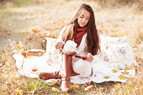 Young beautiful brunette drink tea in the autumn park — Stock Photo, Image