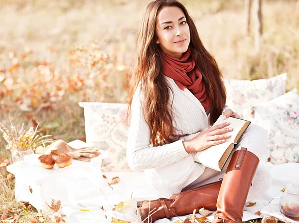 Young beautiful brunette drink tea and read book in the autumn park — Stock Photo, Image