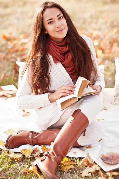 Sonbahar parkta genç güzel esmer içecek çay ve okuma kitabı — Stok fotoğraf