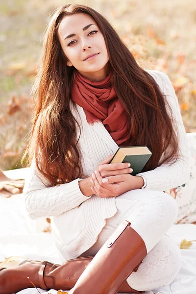 Young beautiful brunette drink tea and read book in the autumn park — Stock Photo, Image