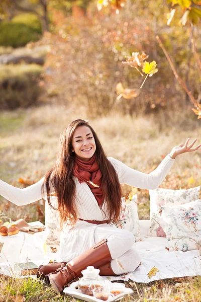 Porträt einer glücklichen Frau, die im Wald mit Herbstblättern spielt — Stockfoto