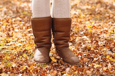Sonbahar ormandaki kahverengi uggs kadının bacaklarını açıp