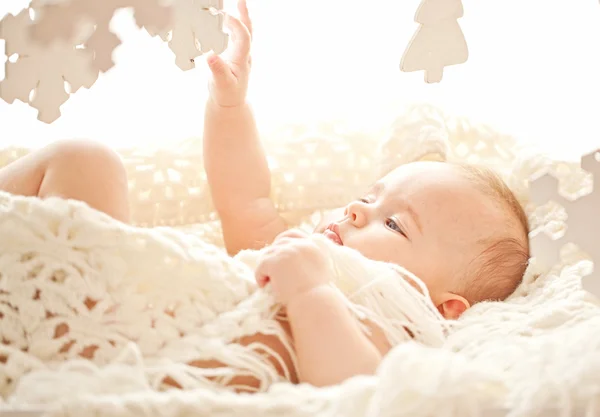 Cute little girl play with wood snowflakes in her cozy white bed — Stock Photo, Image