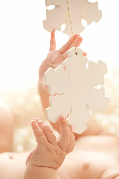 Carino bambina giocare con i fiocchi di neve di legno nel suo accogliente letto bianco — Foto Stock