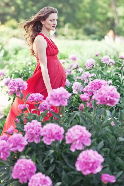 Happy pregnant woman hugging her stomach on the background of pe — Stock Photo, Image